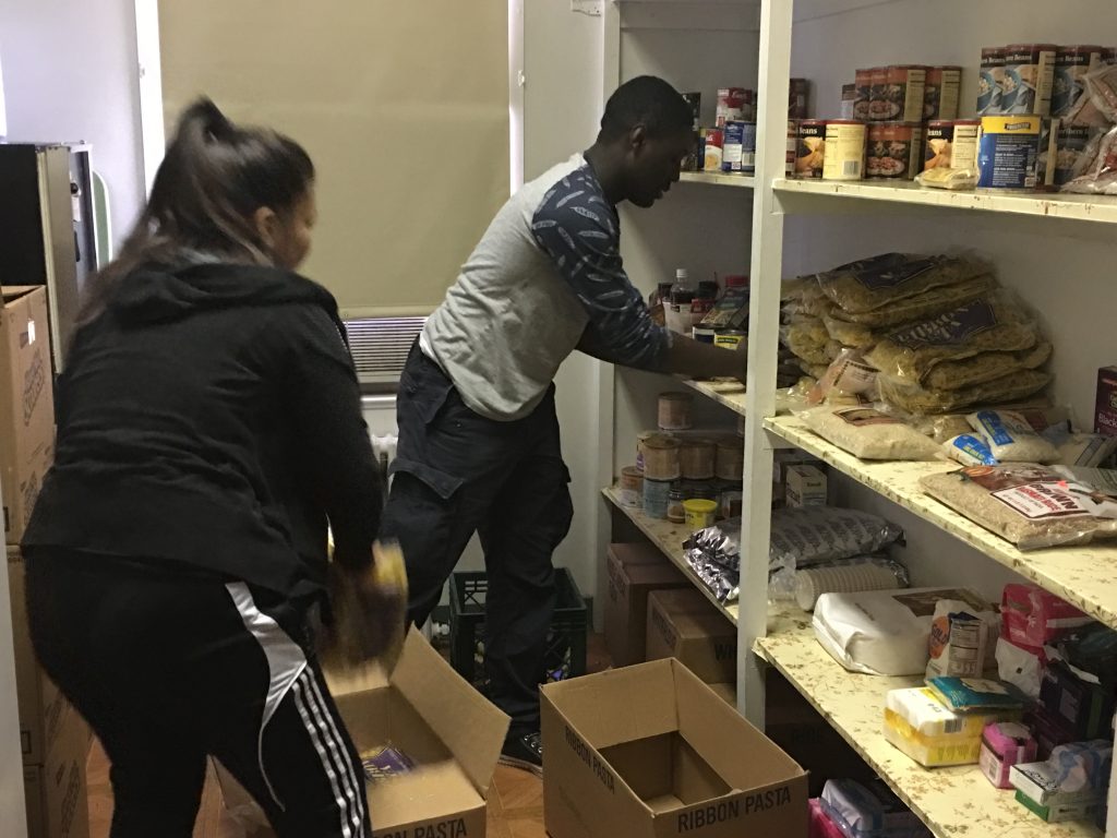 Two volunteers restocking and organizing the pantry